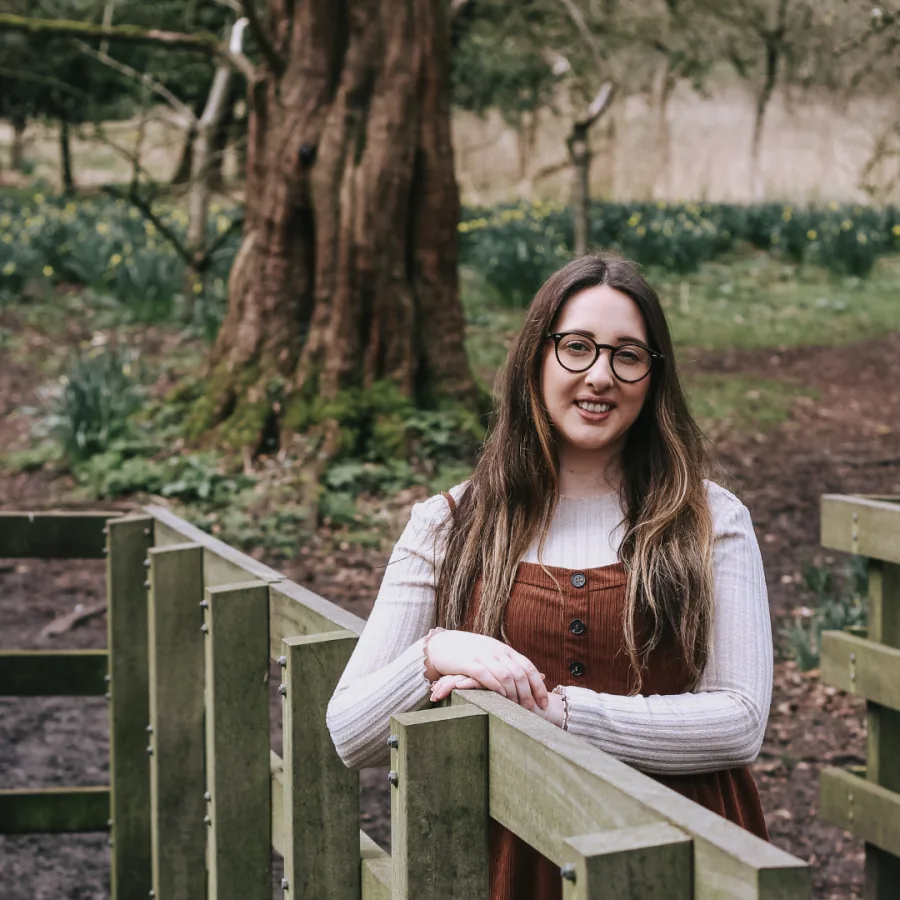 Jen Pepler standing by a wooden railing in a woodland setting